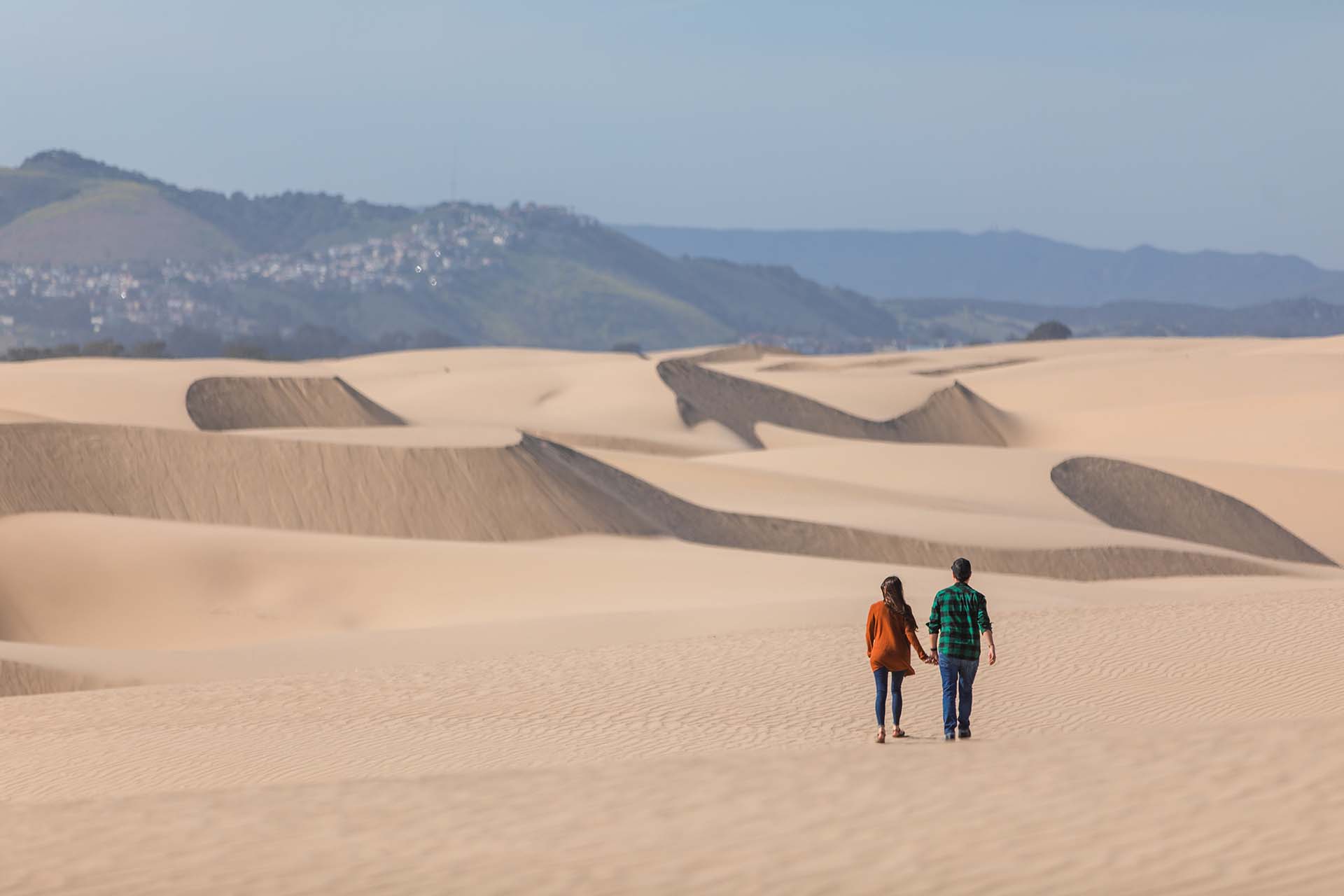 A couple walking on sand dunes at the Oceano Dunes